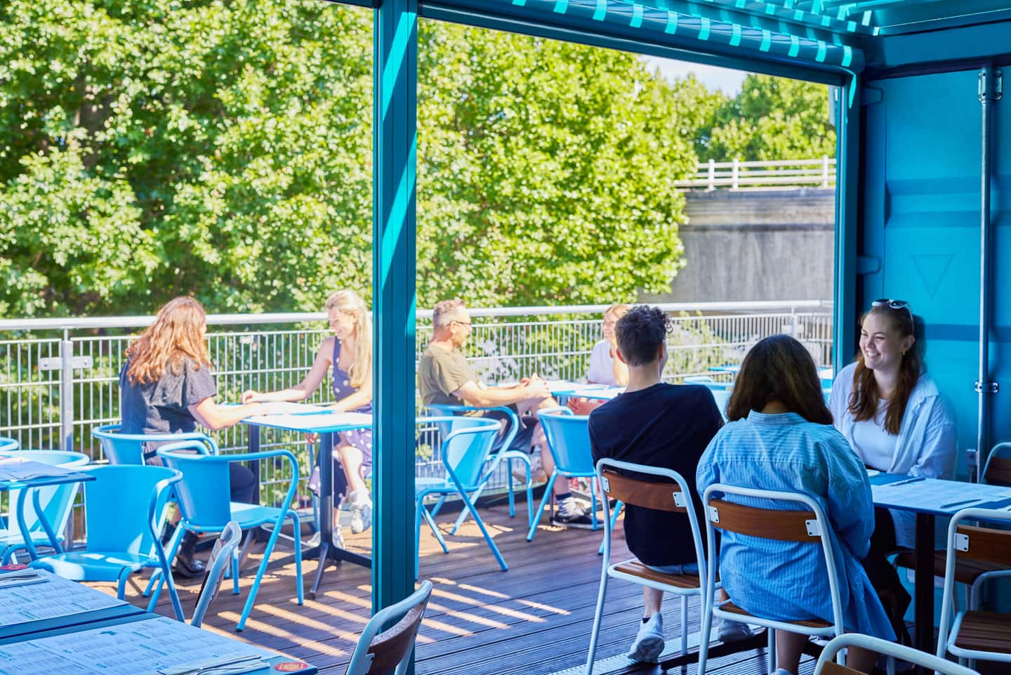Terrace seating outside upstairs at Wahaca Southbank, with a view over the Southbank and river thames with people sitting at tables in a relaxed atmosphere