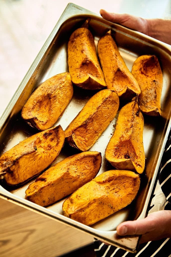 A large steel tray holds freshly roasted organic butternut squash