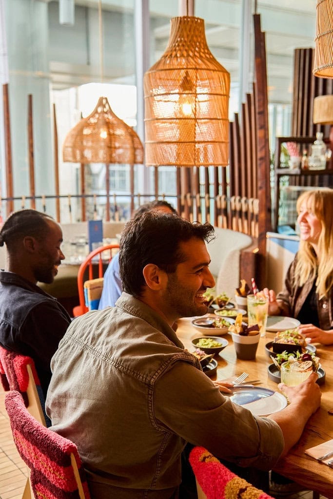 A group of friends enjoy their lunch as they sit at a table in our Mexican restaurant in London Paddington. They have a selection of Mexican food, including tacos, guacamole and cocktails.